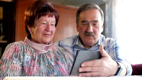 An-elderly-couple-communicates-with-their-grandchild-by-video-linking-the-tablet.-A-man-and-a-woman-are-talking-to-relatives