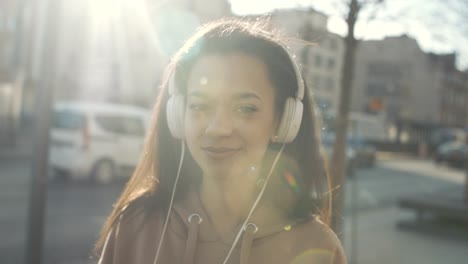 Mujer-joven-con-auriculares-disfrutando-en-una-ciudad.