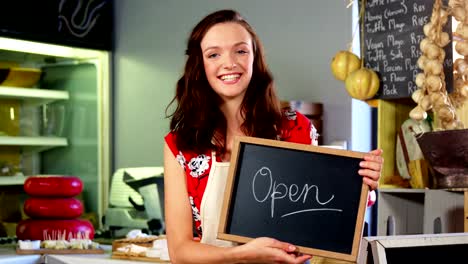 Portrait-of-a-female-staff-holding-a-open-sign