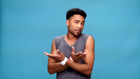 Young-serious-african-man-looking-at-watch-and-waiting-over-blue-background.