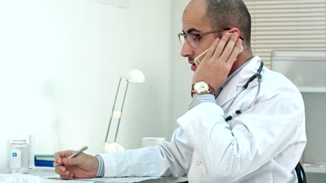 Médico-joven-árabe-tener-conversación-de-teléfono-en-su-oficina