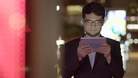 Young-Asian-Man-Using-Tablet-in-Urban-Environment.-Symbolizes-Global-Communication,-Digital-Technology,-Modern-Lifestyle