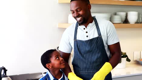 Smiling-father-and-son-standing-together-in-kitchen