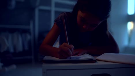 Pleasant-little-girl-doing-her-home-work-in-the-evening-at-home