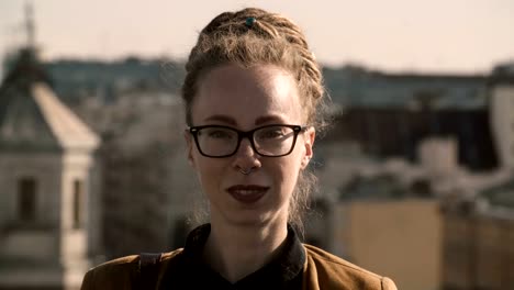 Portrait-of-beautiful-woman-with-dreadlocks-and-piercings-looking-at-camera-and-smiling-against-background-of-panorama