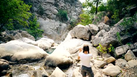 Young-tourist-woman-taking-photo-of-beautiful-canyon-on-her-smartphone-camera-during-travel