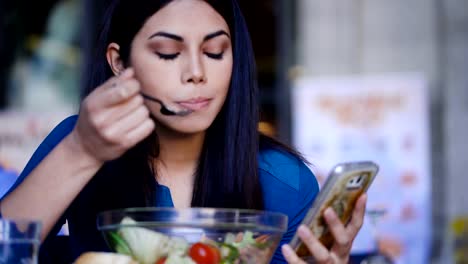 Asian-Woman-Texting-On-Smartphone-And-Eating-Salad-In-Restaurant