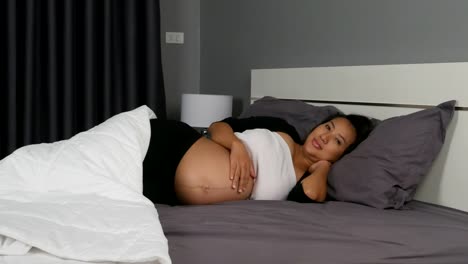 Panning-shot-of-pregnant-woman-while-lying-on-the-bed