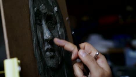 Close-up-of-Sculptor-creating-sculpture-of-human's-face-on-canvas-in-art-studio