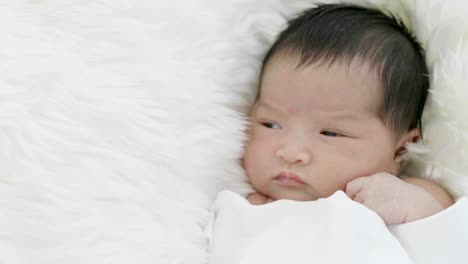 4K-Nahaufnahme-von-asiatisches-Baby-auf-einer-weichen-Decke-verlegen