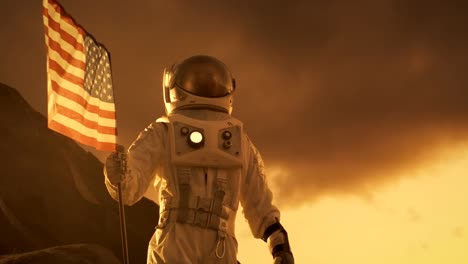 Astronauta-con-traje-espacial-planta-la-bandera-estadounidense-en-el-planeta-rojo-/-Marte.-Momento-patriótico-y-orgullo-para-toda-la-humanidad.-Recorrido-de-espacio-y-concepto-de-colonización.