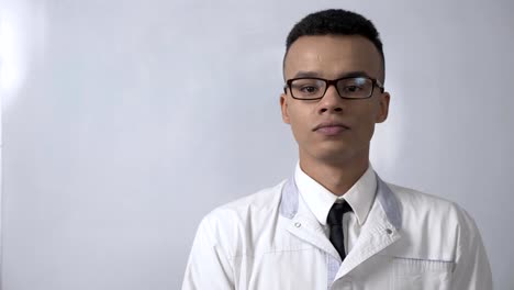 Young-successful-African-scientist-in-a-white-coat-and-glasses-showing-stop-sign,-no,-never-gesture,-crossed-his-arms,-looking-at-the-camera,-portrait-concept.-60-fps