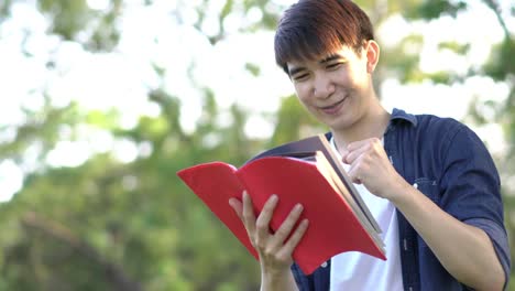 Gut-aussehend-Student-Mann-stand-und-roten-Buch-in-der-hand-zu-halten.-Männlichen-glücklich-Lebensstil.-Konzept-Bildung.