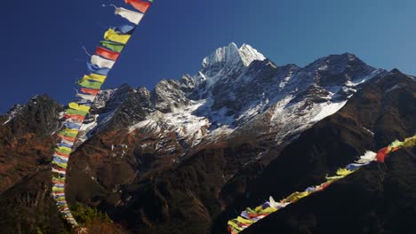 Multi-colored-Buddhist-flags-ripple-in-the-wind-against-the-background-of-snow-capped-mountains