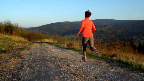 Junge-sportliche-Frau-läuft-im-Freien-bei-Sonnenuntergang-in-Berglandschaft.