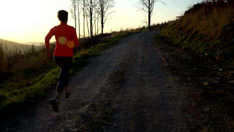 Young-athletic-woman-is-running-outdoor-at-sunset-in-mountain-landscape.