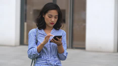 Young-asian-woman-using-smart-phone-in-the-street