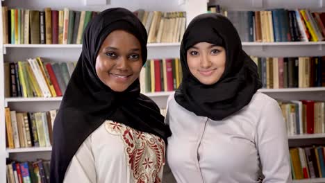 Retrato-de-dos-mujeres-musulmanas-bastante-jovenes-en-biblioteca-y-sonriendo,-amigos-islámicos