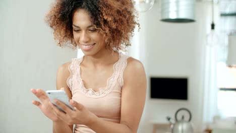 Beautiful-young-afro-american-woman-texting-on-mobile-phone-at-home.