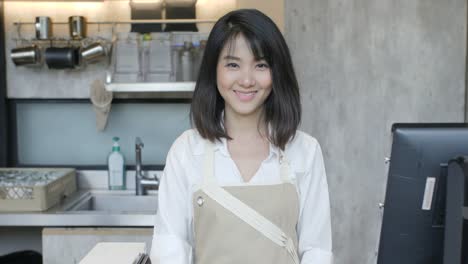 Porträt-von-asiatischen-weiblichen-Barista-über-Hände-und-lächelnd-auf-die-Kamera-im-Kaffee-café