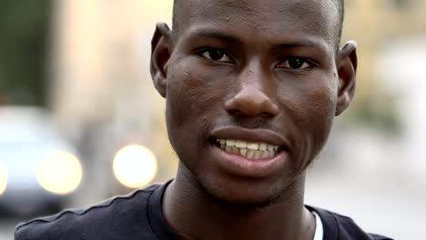 African-american-young-man-smiling-at-camera-in-the-street