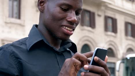 Modernity,technology,youth.-Young-black-african-man-typing-on-smartphone-outdoor