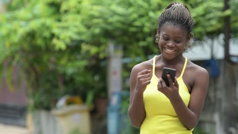 Junge-glücklich-Afrikanerin-mit-Telefon-im-freien