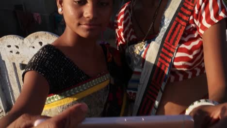 Handheld-shot-of-two-beautiful-cheerful-happy-women-taking-selfie-video-photo-together-with-a-smart-phone-helping-each-other-bonding-love-assist-medium-shot-outdoor-rural-Indian-Asia-south