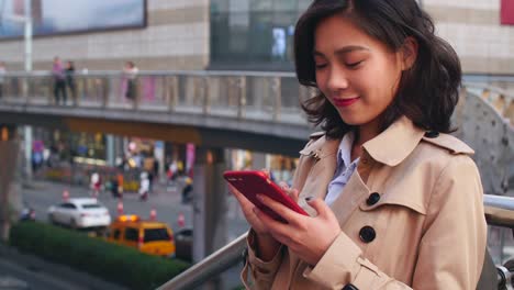 una-mujer-joven-mirando-su-teléfono-móvil-en-la-calle