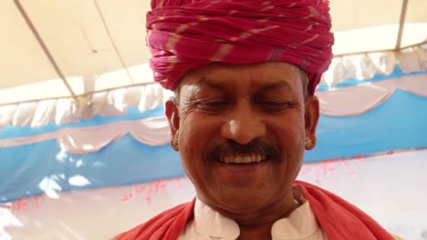 Handheld-Indian-man-busy-on-a-touchscreen-tablet-with-a-wonderfully-colourful-tent-backdrop