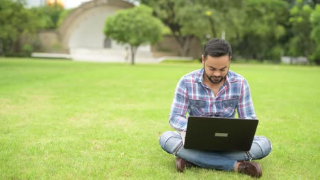 Schönen-jungen-indischen-Mann-im-Park-mit-Laptop-Computer