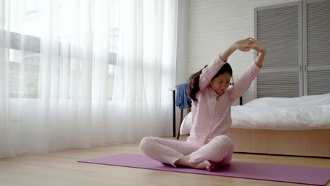 Frau-sitzt-auf-der-Yoga-Matte-und-bewegte-ihre-Hände