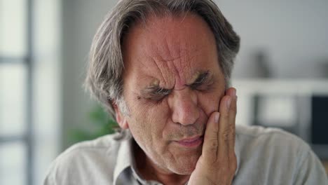 Hombre-con-los-dientes-sensibles,-sosteniendo-un-vaso-de-agua-fría