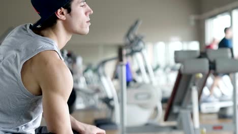 A-shirtless-guy-at-the-gym,-trains-his-body-to-stay-fit-and-have-defined-muscles.-The-athlete-raises-heavy-weights-and-fatigue.