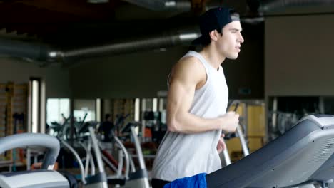 Un-chico-sin-camiseta-en-el-gimnasio,-entrena-su-cuerpo-para-mantenerse-en-forma-y-han-definido-los-músculos.-El-atleta-provoca-fatiga-y-cargas-pesadas.