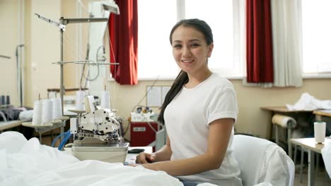 Joven-sonriente-costurera-a-máquina-de-coser