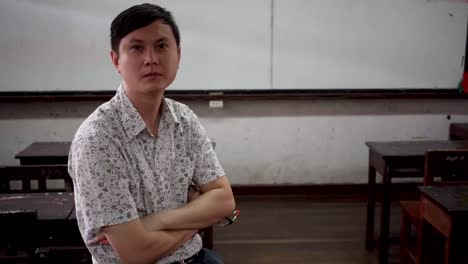 Portrait-of-young-handsome-Asian-male-teacher-smiling-inside-the-classroom