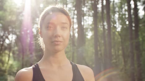 Stets-gut-gelaunte-Frau-posiert-im-Wald-auf-sonnigen-Tag