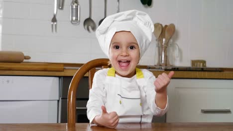 Portrait-of-two-sisters-in-the-kitchen-dressed-as-professional-chefs-who-smile-and-kisses-looking-at-the-camera-with-their-arms-folded-by-real-professional-chefs.