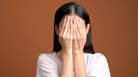 Chica-jugando-oculta-y-busca-el-retrato.-Mujer-asiática-en-camiseta-blanca-cubra-sus-ojos-con-sus-manos-para-ocultar-y-buscar.