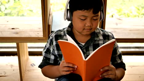 Süße-asiatische-Kinder-ein-Buch-lesen-und-hören-Sie-Musik-zu-Hause.-Bildungskonzept