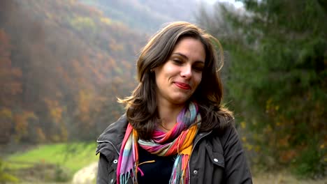 A-beautiful-young-girl-is-standing-in-the-autumn-forest,-looking-at-the-camera-and-smiling.-She's-happy.