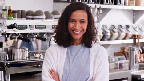 Young-female-coffee-shop-owner-crossing-arms,-close-up