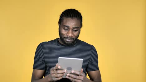 Casual-African-Man-Excited-for-Success-while-Using-Tablet-Isolated-on-Yellow-Background