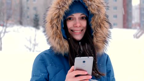 Mujer-hermosa-joven-escribiendo-un-mensaje-en-su-teléfono-celular,-mirando-a-cámara-y-sonriendo.