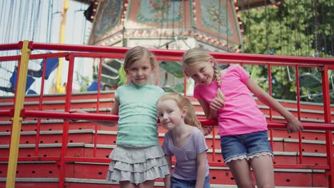 Three-little-girls-smiling-in-front-of-a-carnival-ride