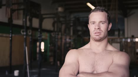 A-fit-young-man-at-a-small-gym-crossing-his-arms-and-staring-at-the-camera