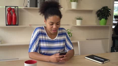 Happy-woman-using-app-on-mobile-phone-at-the-office