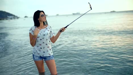 Fröhliche-Brünette-Frau-selbst-fotografieren-an-einem-wunderschönen-Strand.