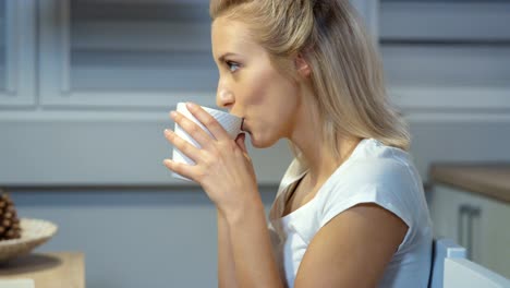 Fröhliche-Junge-Frau,-die-Tasse-in-die-Küche-zu-Hause-hält.